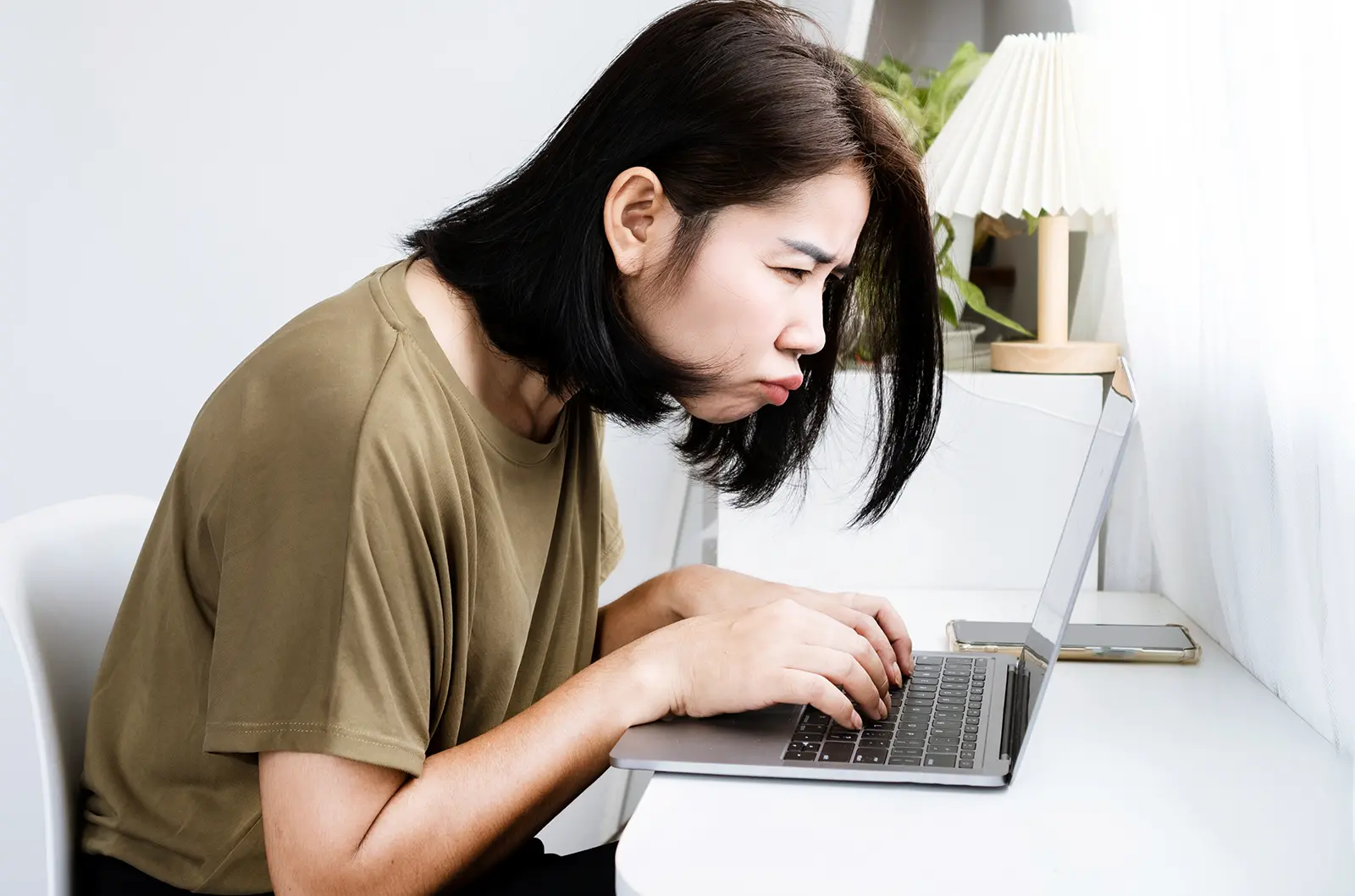 Giovane donna che guarda il computer da vicino in modo confuso